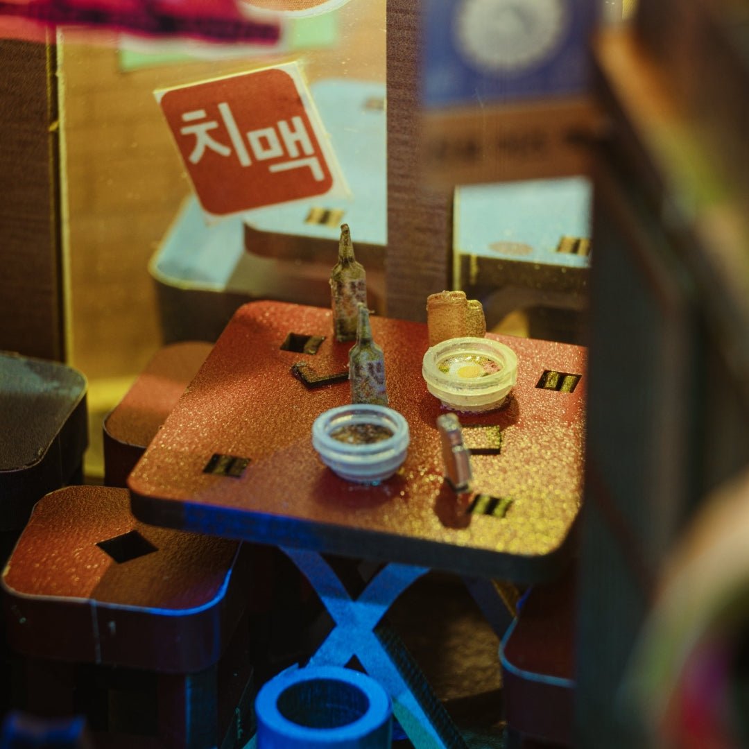 Tiny wooden table with soju bottles and snacks inside the Seoul Hipjiro miniature alley