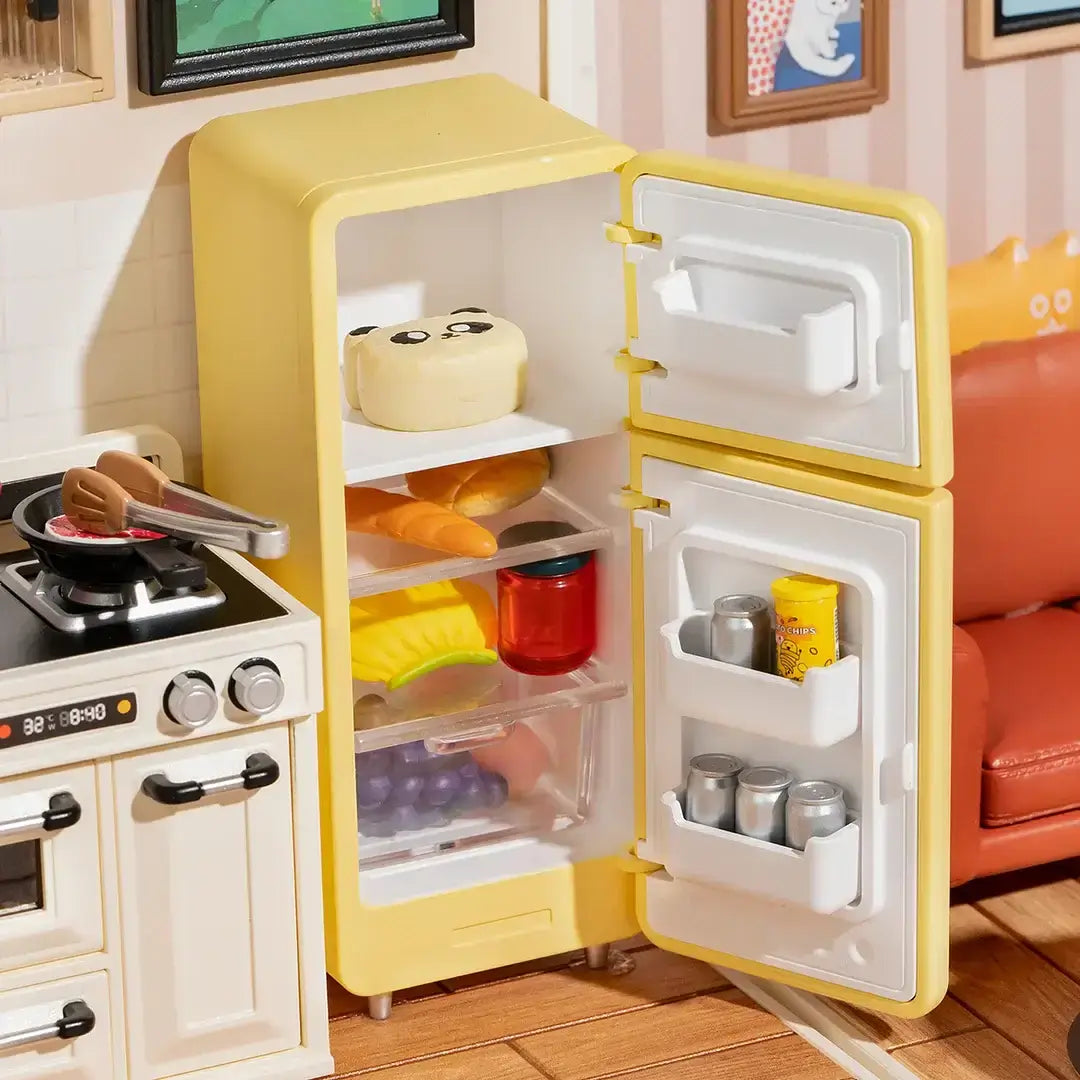 Open yellow refrigerator with miniature food items next to a stove in a DIY plastic Happy Meals Kitchen miniature house.