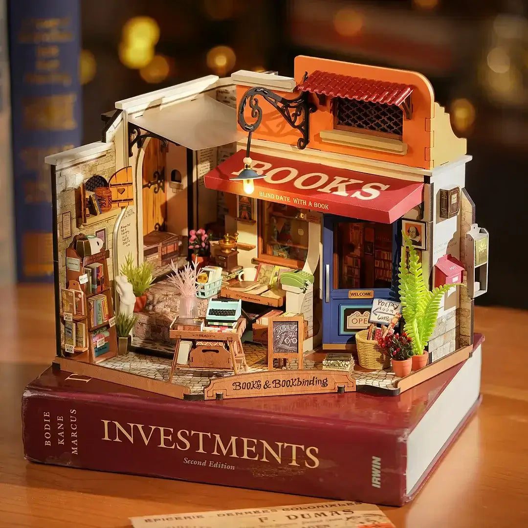 Corner Bookstore DIY Miniature House Kit displayed on a thick book with intricate bookstore details and warm lighting
