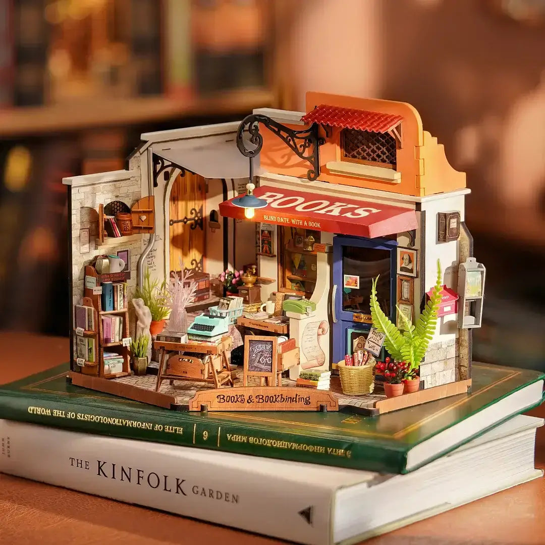 Corner Bookstore DIY Miniature House Kit displayed on books; intricate details of a miniature bookstore model with books and plants.