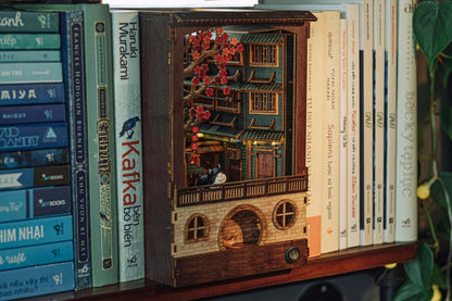 JiuFen Old Street DIY book nook kit with cherry blossoms and traditional Chinese architecture on a shelf with books