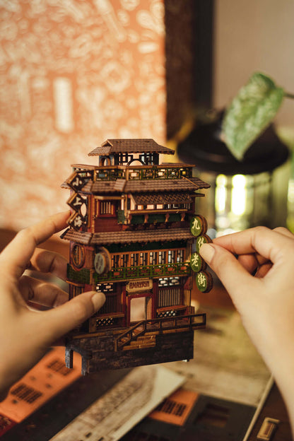 Hands assembling JiuFen Old Street DIY book nook kit depicting a traditional Taiwanese building with vibrant lanterns and cherry blossoms